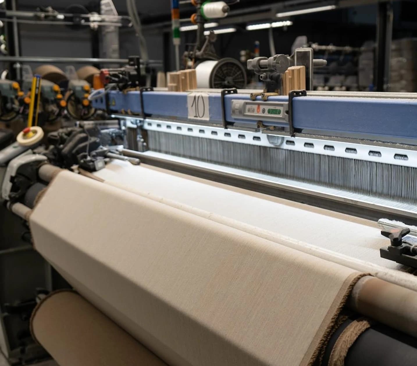 Loom weaving beige fabric onto a roll