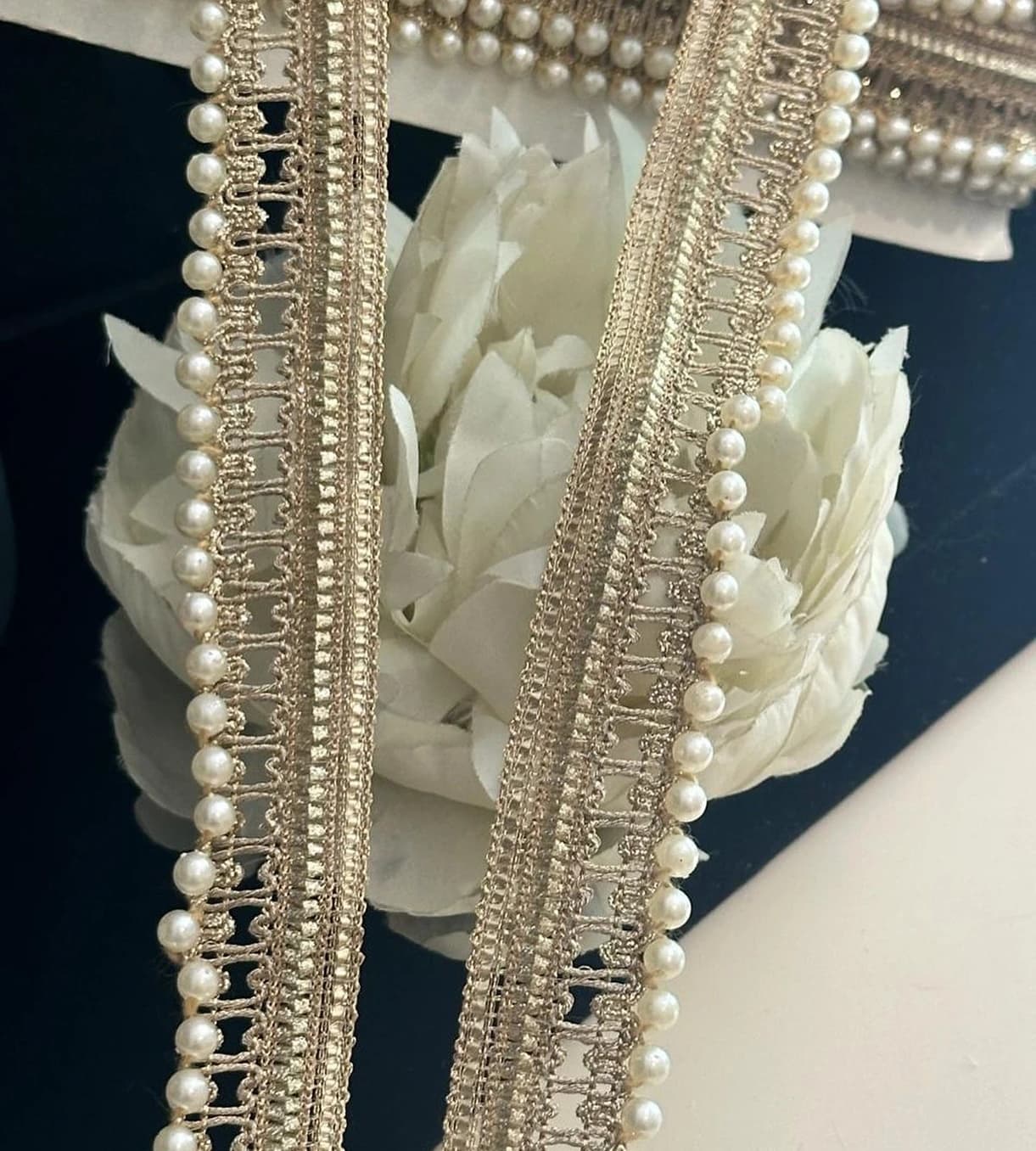 Pearl-edged lace trims laid over white fabric flowers